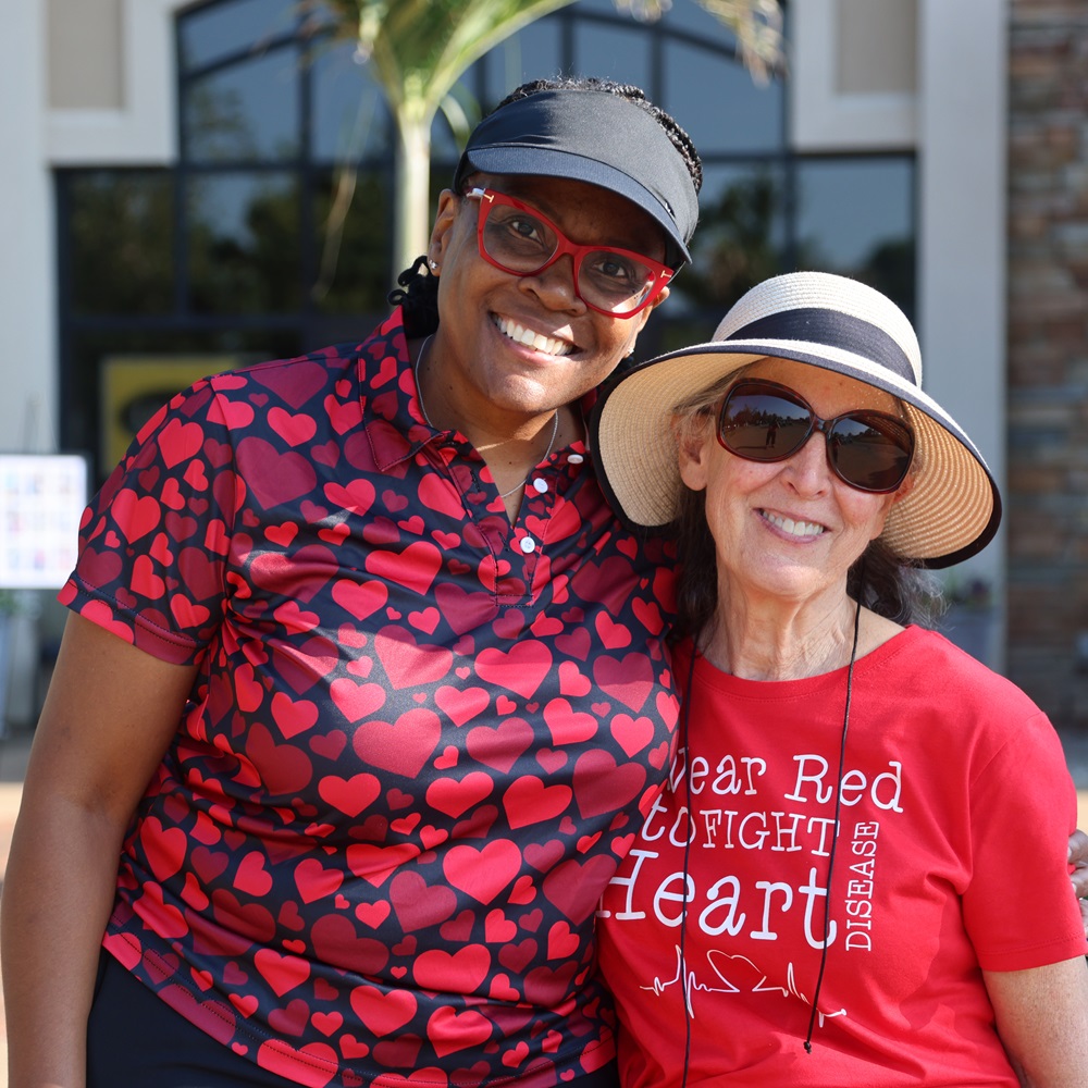 Two women standing together, one in a red shirt reading "Wear Red to fight heart disease".