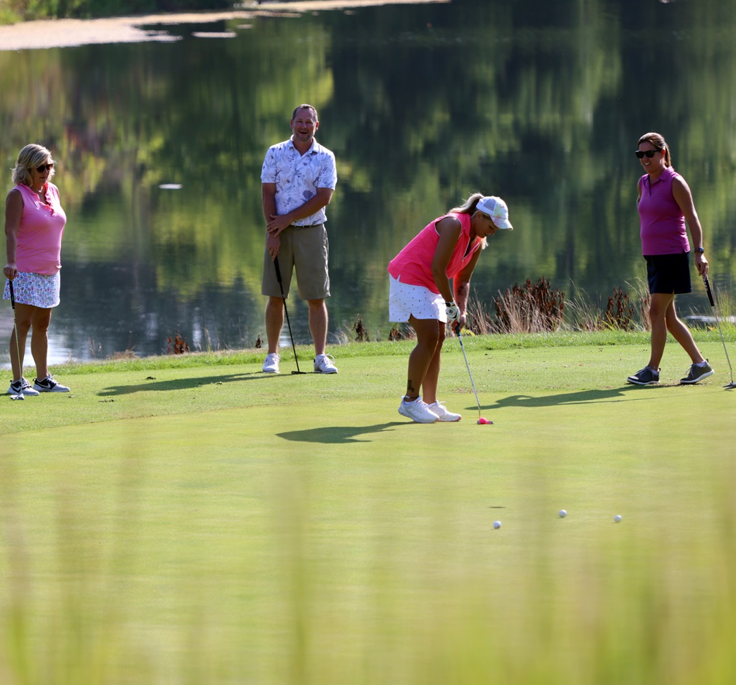 Foursome practicing on the putting green.